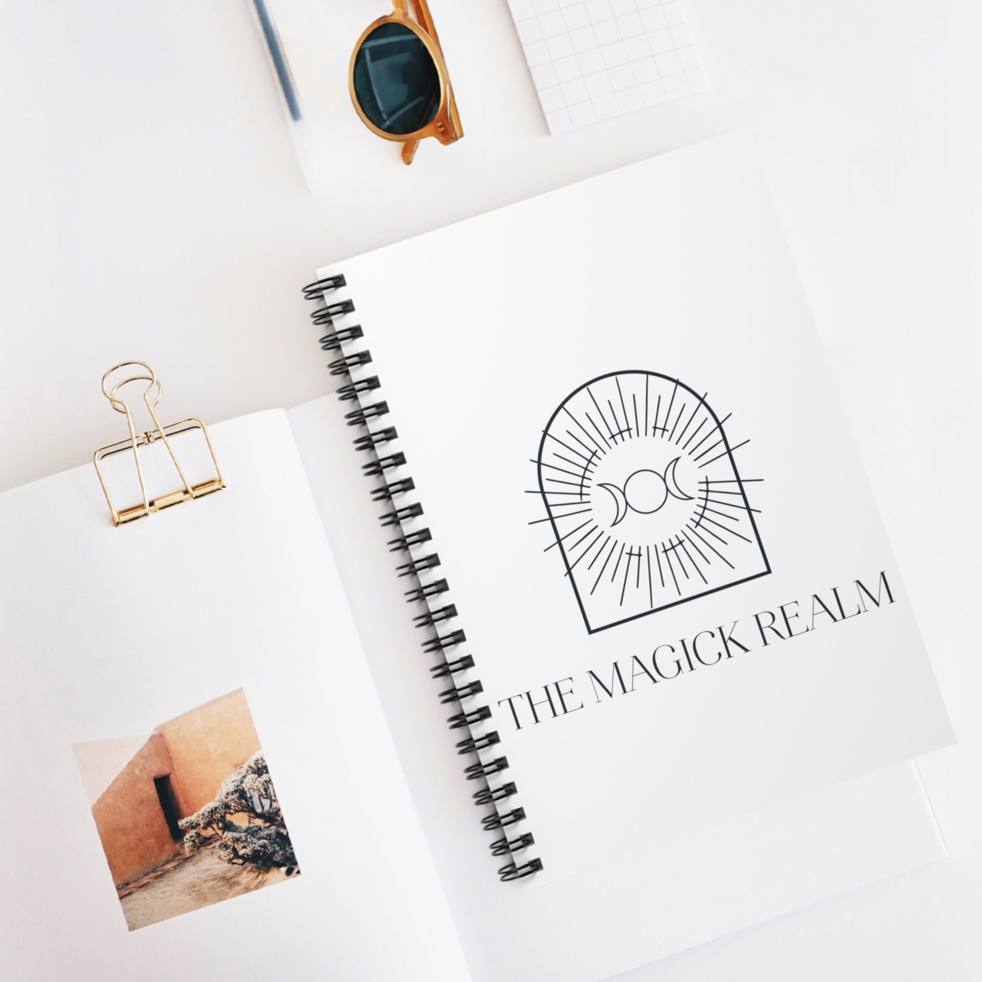 Notebook with 'The Magick Realm' logo on a white surface