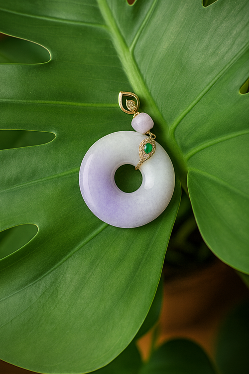 Jade donut pendant with gold and gemstone accents on a green leaf